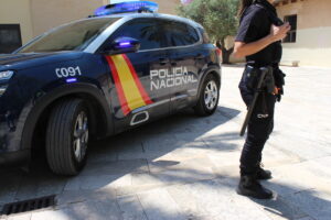 Agente de la Policía Nacional junto a un coche patrulla